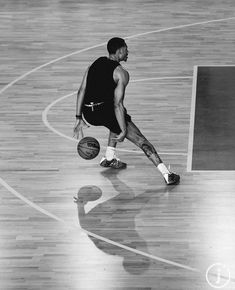 a basketball player dribbling the ball on an indoor court with wood flooring