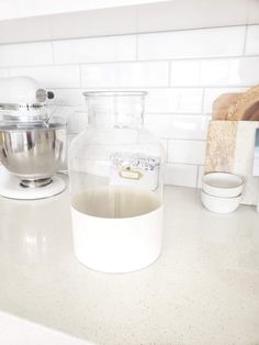 a glass pitcher sitting on top of a kitchen counter next to a bowl and mixer