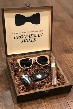 an open box with groomsmly skills in it on a wooden floor next to a bottle of cologne