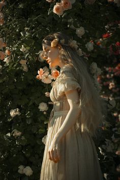 a woman in a white dress standing next to flowers