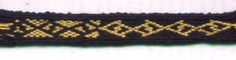 an old black and yellow knitted bracelet with gold designs on it's side