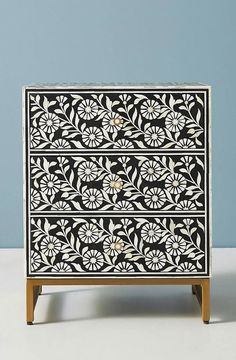 an ornate black and white chest of drawers