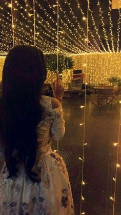 a woman standing in front of a window covered in fairy lights