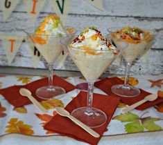 three glasses filled with ice cream and toppings on top of red placemats