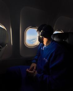 a man is sitting in an airplane looking out the window at the clouds and sky