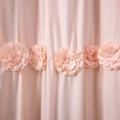 three pink flowers on the side of a white curtain