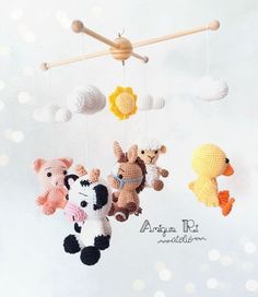 three crocheted animals hanging from a wooden stick on a white background with bubbles