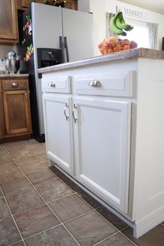 a kitchen with tile flooring and white cabinetry, including an island in the middle