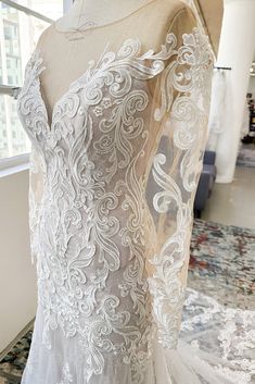 the back of a wedding dress on display in a room with lots of glass windows