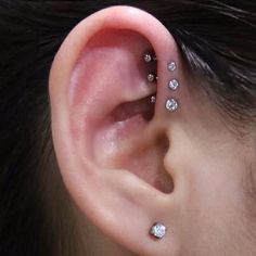 a woman's ear with three small diamond studs