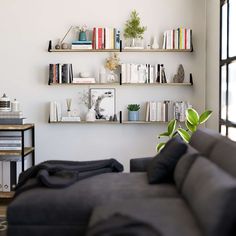 a living room filled with furniture and bookshelves next to a wall mounted book shelf