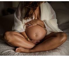 a pregnant woman sitting on top of a bed with her belly wrapped around her stomach