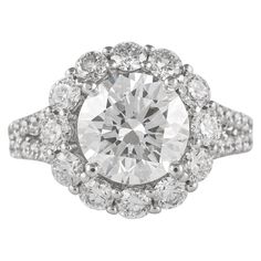 an oval cut diamond surrounded by smaller round diamonds in a halo style setting on a white background