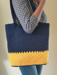 a woman holding a blue and yellow knitted bag