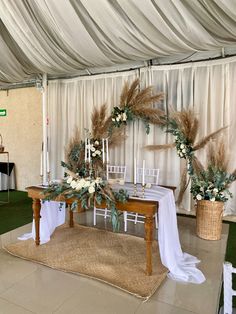 the table is set up with white flowers and greenery on it, along with candles