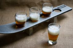 three glasses of beer sit on a metal tray