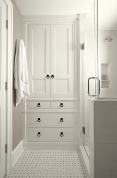 a white bathroom with black and white floor tiles on the walls, cabinets and drawers