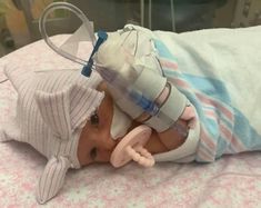 a baby in a hospital bed with an oxygen tube attached to it's head