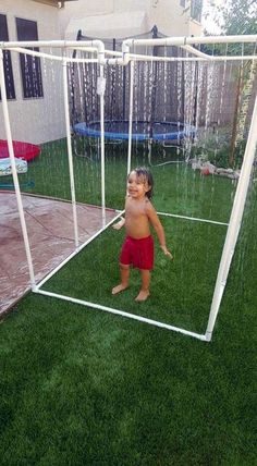 a little boy standing in front of a soccer goal on top of green grass next to a house