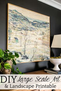 a large scale art and landscape print hangs on the wall above a table with a lamp