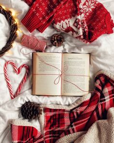 an open book sitting on top of a bed next to two candy canes and christmas decorations