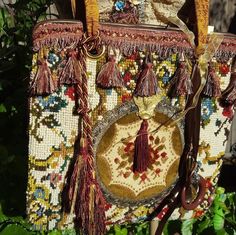 an old purse with tassels hanging from it's side in the grass