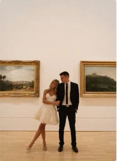 a man and woman standing next to each other in front of paintings