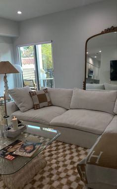 a living room filled with furniture and a large mirror on top of the wall next to a window