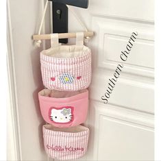 three baskets are hanging on the wall in front of a door with hello kitty stickers