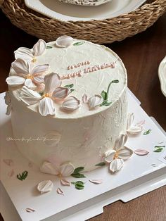 a white cake sitting on top of a wooden table next to a wicker basket