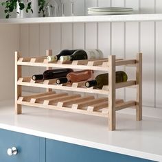 a wooden wine rack with several bottles on top of it in a white and blue kitchen