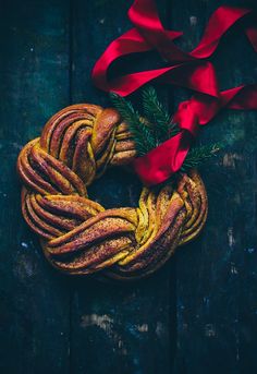 a piece of bread wrapped in red ribbon on top of a wooden table next to a bow