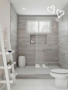 a white toilet sitting in a bathroom next to a shower and sink with a ladder