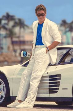 a man sitting on top of a white sports car