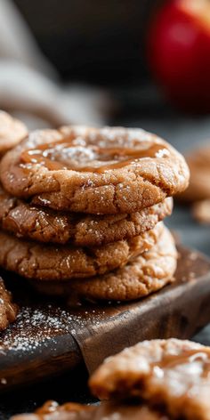 a stack of cookies sitting on top of a wooden cutting board next to an apple