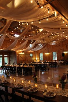 a banquet hall decorated with candles and white draping