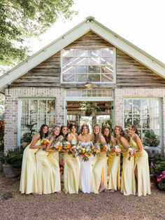 a group of women standing next to each other in front of a building with flowers