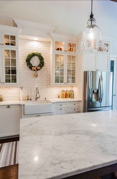 a kitchen with marble counter tops and white cabinets, along with an island in the middle