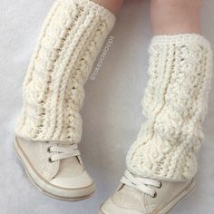 a child's legs wearing white knitted socks and booties with laces