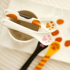 two toothbrushes with paw prints on them are sitting in a cup next to a spoon