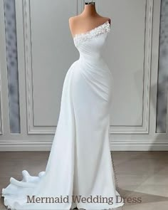 a white wedding dress with an off the shoulder neckline