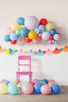 a pink chair sitting in front of balloons