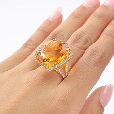 This exquisite cocktail ring features a radiant Citrine gemstone as its centerpiece, enveloped by sparkling White Topaz accents. The Citrine's vibrant yellow hue is complemented by the intricate detailing of the White Topaz, all set in a luxurious gold-plated band. The design of the ring is inspired by the Art Deco era, known for its bold geometric patterns and lavish ornamentation. The ring's elegant curves and striking symmetry make it a timeless statement piece, perfect for any special occasi Yellow Rings With Gemstone Accents For Formal Occasions, Formal Yellow Rings With Gemstone Accents, Formal Citrine Ring With Diamond Accents, Formal Yellow Topaz Ring With Diamond Accents, Yellow Rings With Accent Stones For Formal Occasions, Formal Yellow Topaz Ring With Accent Stones, Elegant Yellow Topaz Ring, Orange Rings With Gemstone Accents For Formal Occasions, Yellow Topaz Ring With Gemstone Accents