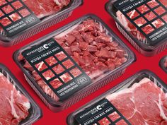 four packages of raw meat sitting on top of a red table with black and white labels