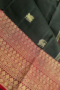 This banarasi inspired stunning kanjivaram saree in kanchana black is handwoven with traditional motifs in gold zari on the body. The borders in deep maroon have traditional motifs like floral, chakras and geometric patterns in gold zari. The grand pallu in deep maroon color mirrors the patterns of the borders in gold zari. Approximate Length 6.5 mtrs (inclusive of blouse length) Approximate weight - 1.5 lbs Approximate Height - 48 - 52" Saree comes with fall, picot and tassels done when applicable. Blouse piece is cut. Kindly Note : The colors you see on your device may vary due to the color reproduction, brightness and resolution of individual devices. If you'd like more clarity before your purchase, please contact our support team. Black Raw Silk Saree With Cutdana, Black Raw Silk Saree With Zari Work, Black Raw Silk Saree With Pallu, Black Tussar Silk Dupatta For Navratri, Black Tussar Silk Saree For Festivals, Bollywood Style Black Handloom Dupatta, Black Chanderi Saree With Zari Weaving, Black Paithani Silk Handloom Dupatta, Black Handloom Anarkali Dupatta