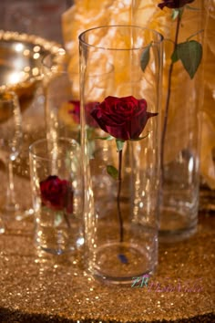 red roses are placed in glass vases on a gold sequined table cloth