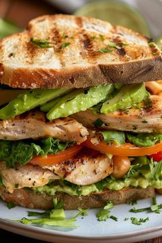 a grilled chicken sandwich with lettuce, tomato and cucumber on toasted bread