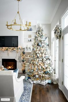 a living room decorated for christmas with a large white tree and fireplace in the corner