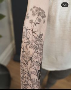 a woman's arm with flowers and leaves tattooed on the back of her arm