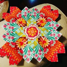 a colorful paper flower sitting on top of a wooden table